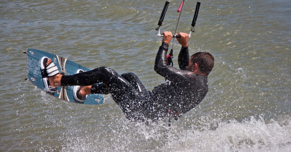 Person wearing a wetsuit in the water holding onto a kite harness