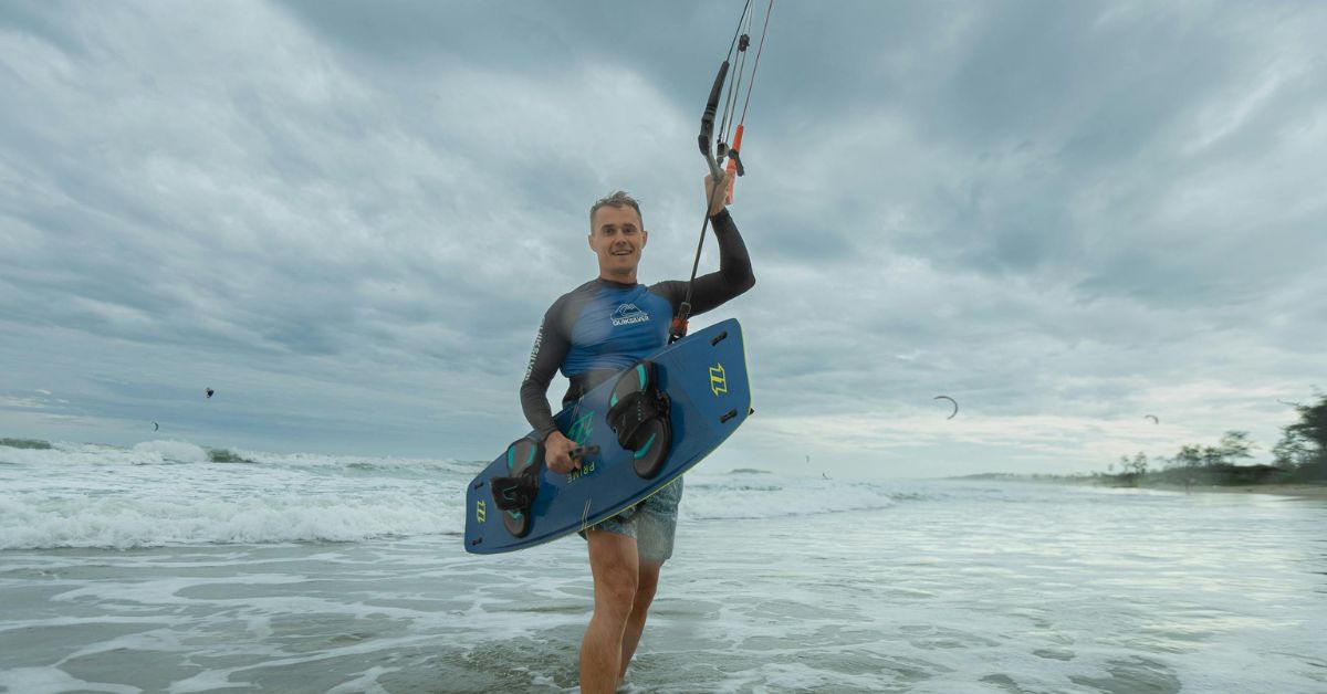 Man holding up his kiteboard whilst in the ocean