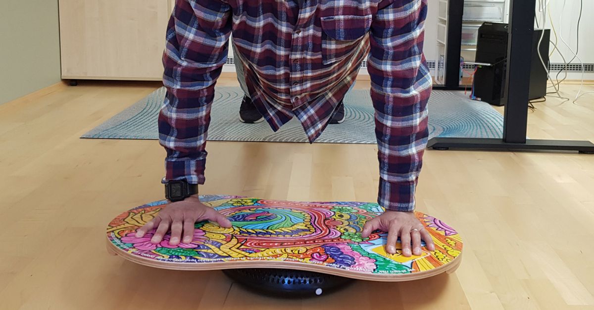 Man doing push ups on a colourful piece of wood in his home office
