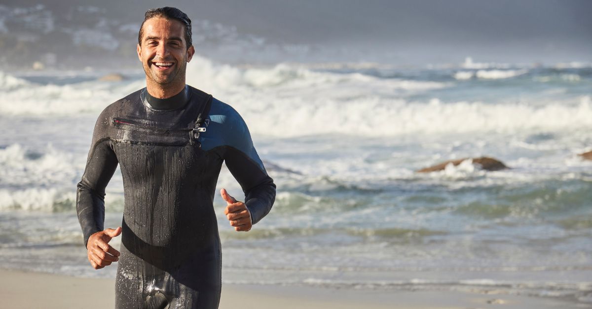 Man running by the ocean in a wetsuit