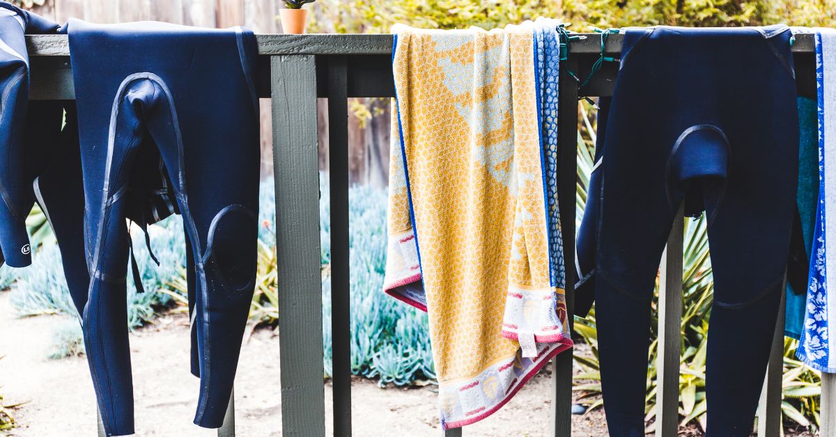 Wetsuits and towels drying on a rail