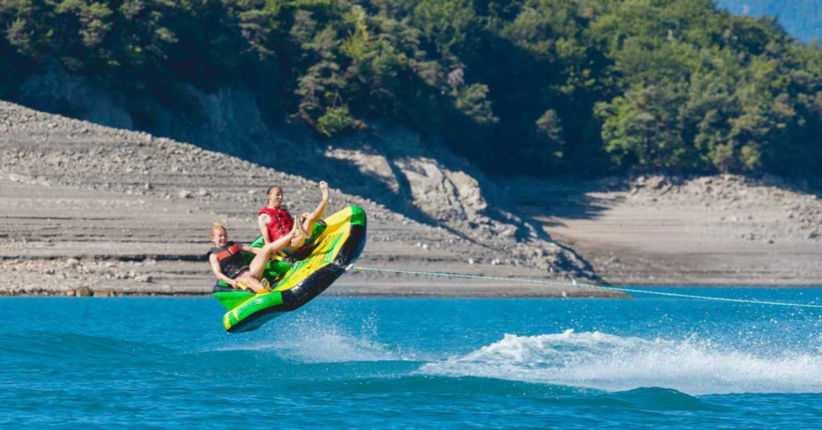 A tube jumping on the water with two people in it.