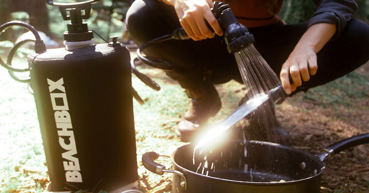 Person using a portable hose to spray a knife over a pot
